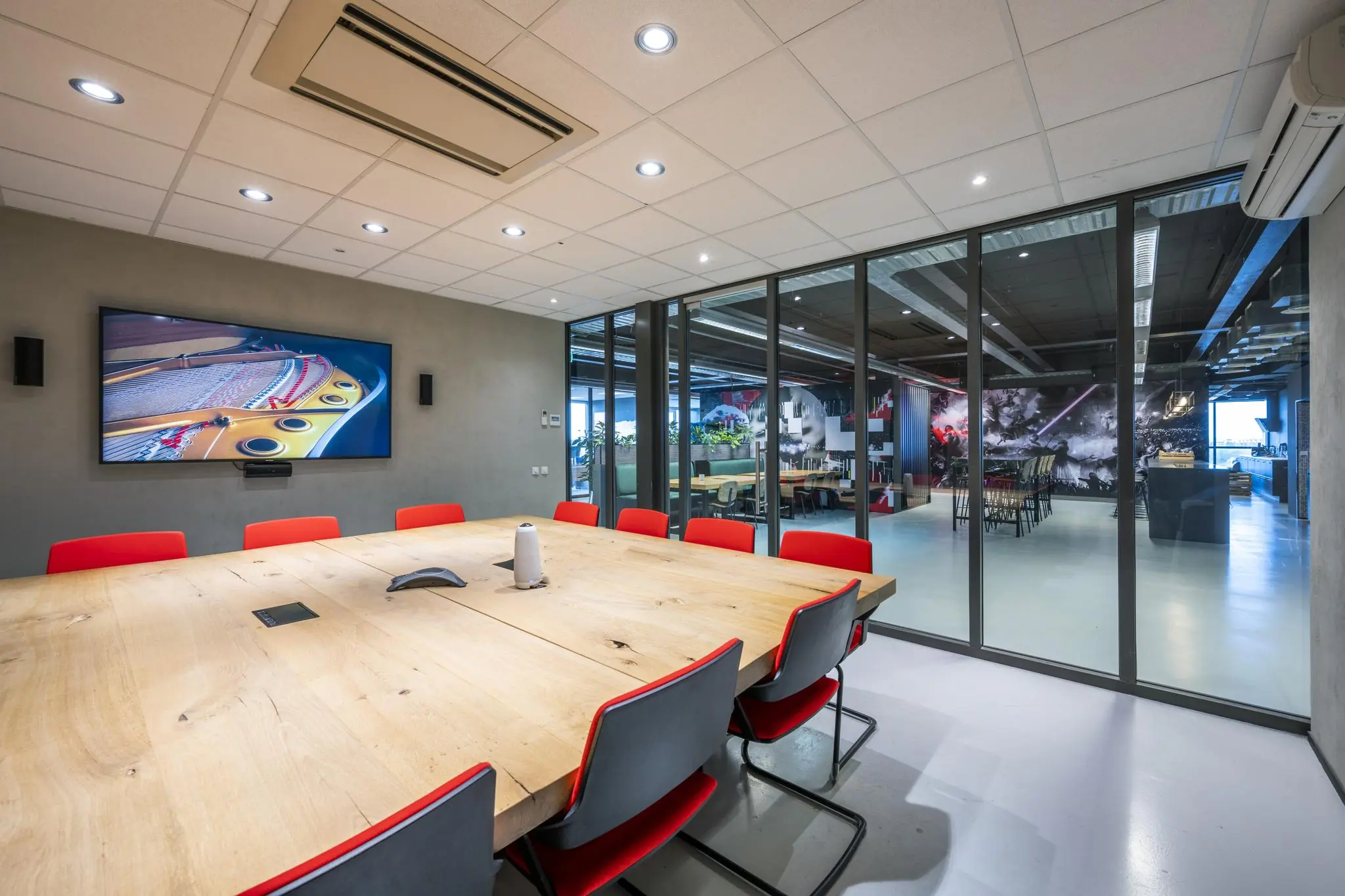 Moderne vergaderruimte aan de Anthony Fokkerweg met houten tafel, rode stoelen en glazen wand met uitzicht op creatieve kantoorruimte.